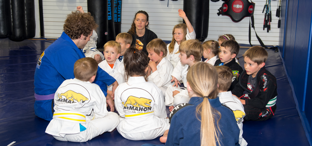children martial arts student gathered in circle listening to their coach talk