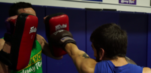 kickboxing instructor in blue shirt and red boxing gloves, throws a left cross