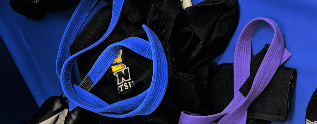 Jiu-jitsu blue and purple belts on top of black jiu-jitsu gi