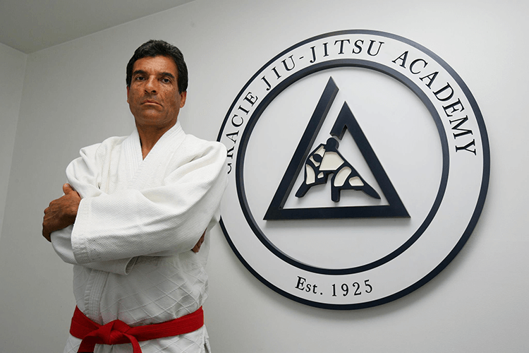rorion-gracie standing in white gi next to gracie jiu-jitsu academy logo