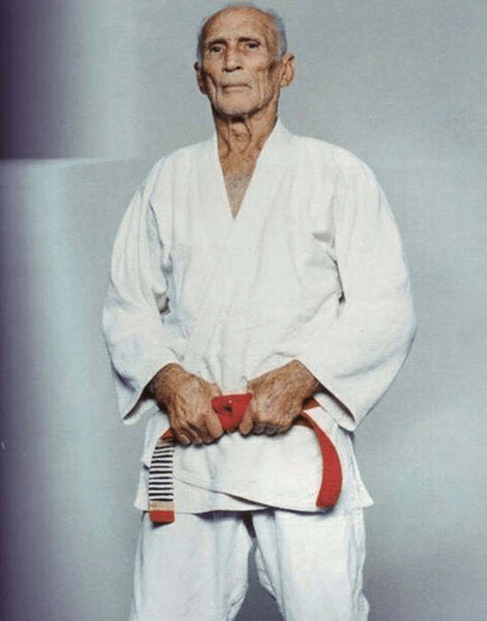 Helio gracie in white gi standing with hands on jiu-jitsu red belt