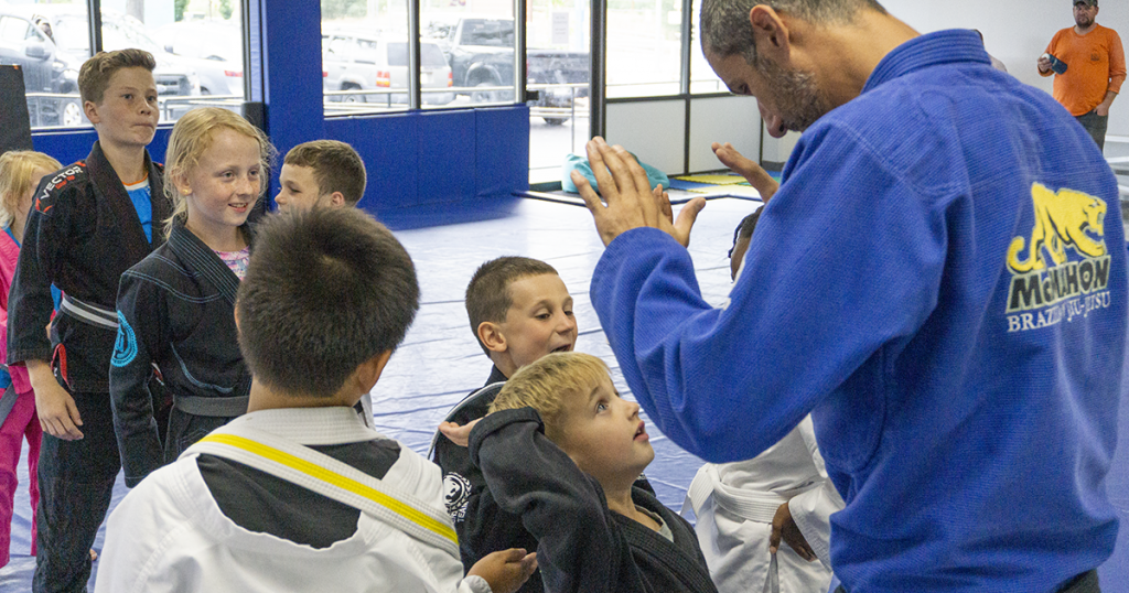 jiu jitsu black belt in blue gi high fiving child martial artist